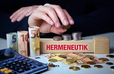 Hermeneutik. Hand baut Geldstapel auf einem Baustein mit Text. Turm aus Euro Münzen....