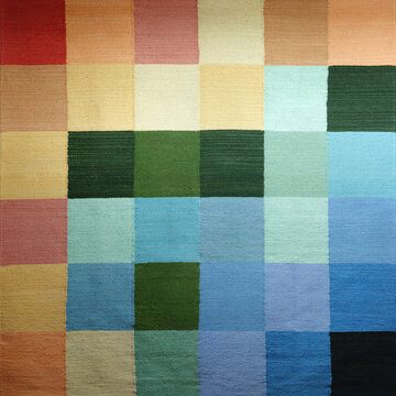 Abstract handicraft art of colored squares, hand woven wool with natural dyes