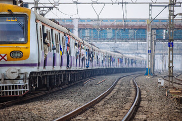 Train full of people traveling through a railway station in Mumbai, India