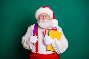 Portrait of his he nice handsome overweight bearded cheerful Santa holding in hands copy book materials going back to school autumn season isolated over green color background