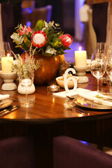 Proteas in a round copper vase with warm lighting.