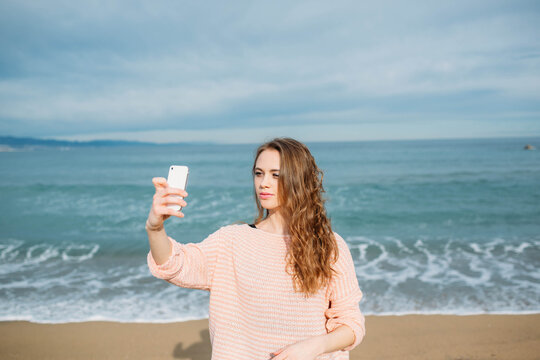 Blonde woman taking a selfie with the sea in the background