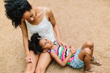 A mother and daughter sit on the ground and have a talk.