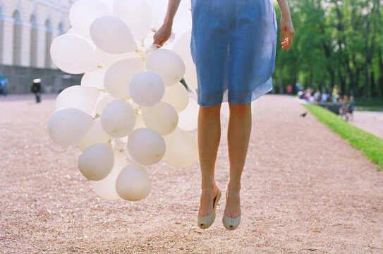 Woman jumping with white balloons
