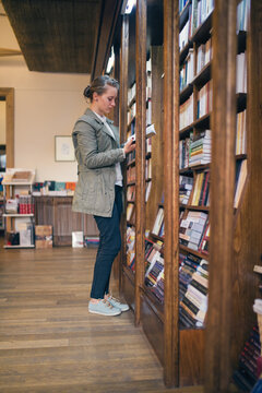 Woman in a library reading by the bookcase