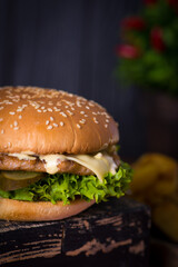 hamburger on black background, juicy burger on a plate with a red napkin and potatoes on a black wooden background