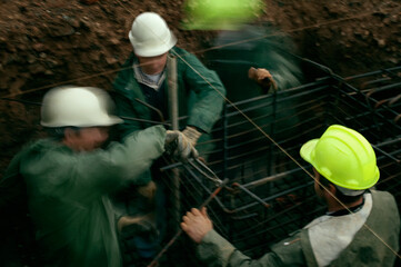Team of masons working together to fix a rebar structure for a foundation