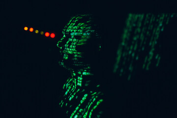 Young man with geen abstract letters on his face in the dark.