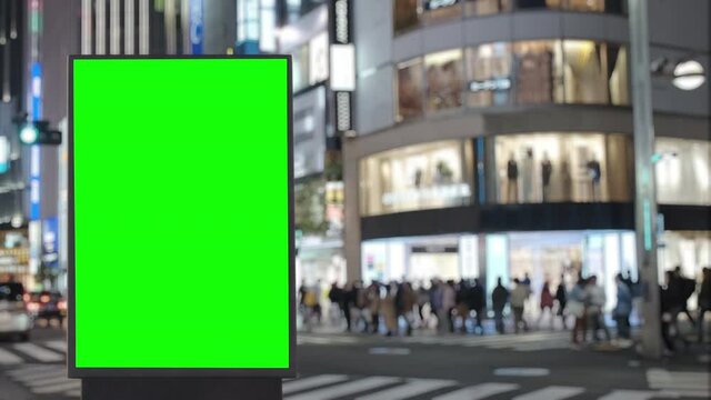 Modern billboard with a green screen on a crowded crossroad with traffic, neon lights at night, Tokyo, Japan