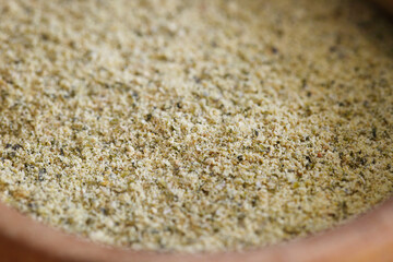 Ground pepita pumpkin seeds in wooden bowl, used for baking.