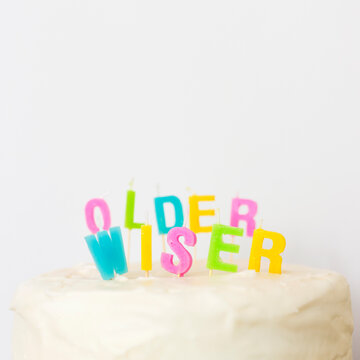 Letter shaped candles saying Older Wiser on cake top