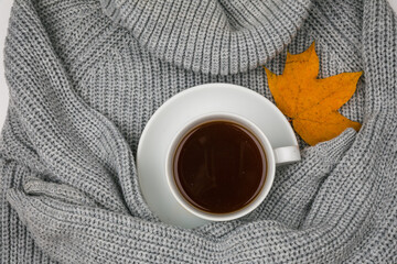 A pile of bright autumn leaves and a Cup of hot tea on a textile knitted sweater background. Flatley