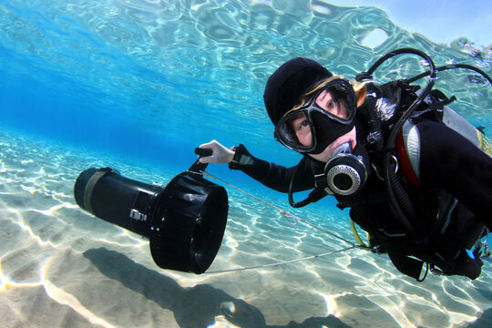Woman taking self while diving with heavy duty underwater scooter in shallow sea water