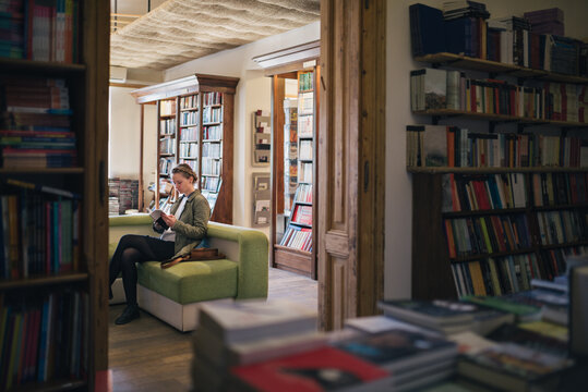 Woman on a couch in a bookstore reading a book