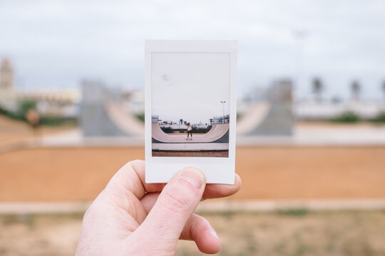 Hand Holding A Picture With a Woman Skateboarder