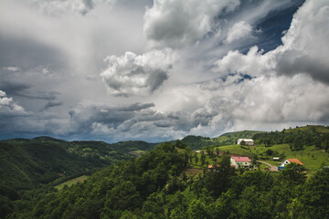 Fototapeta na wymiar Small farm in a mountain village under the cloudy sky in western Serbia