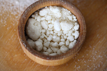 Coconut flour in wooden bowl isolated on brown. Top view.