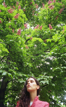 Girl in a pink jacket standing under the flower tree