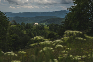 Small white house in a mountain landscape under the cloudy sky in western Serbia