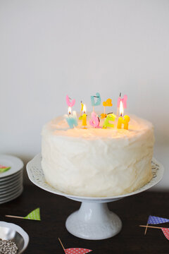 Burning and melted letter shaped candles on cake