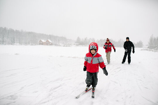 Two men and a boy playing outside on a frozen lake on a snowy day