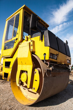 Yellow Road construction maschine for compresing layer of asphalt on road.