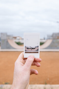 Hand Holding A Picture With a Woman Skateboarder
