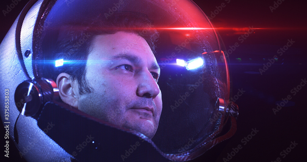 Wall mural young brave male astronaut in space helmet looking at camera slowly. he is exploring outer space in 