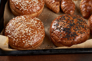 baked sesame buns on brown parchment paper, ingredient for a hamburger