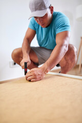 Man assembling furniture in new apartment, moving in and being hardworking.