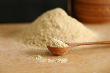 Crushed flax seeds (ground linseed) on wooden spoon and table - healthy organic vegan vegetarian food ingredient