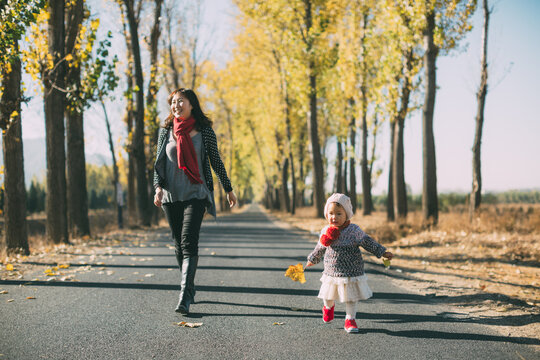 Mother and daughter walking on a road in autunm