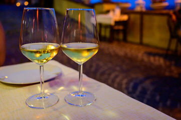Two glasses of cold dry white wine served outdoor in cafe at night in Italy