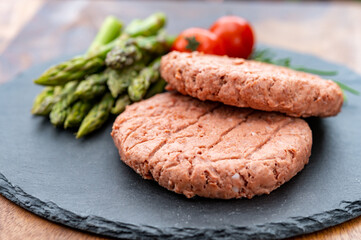 Ingredients for tasty vegan dinner, meat free plants based steak, green asparagus and red tomatoes