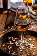 Tasting glasses with aged Scotch whisky or bourbon on old dark wooden vintage table with barley grains