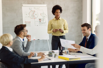 Black female business leader communicating with her team during a presentation in the office.