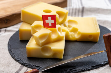Block of Swiss medium-hard yellow cheese emmental or emmentaler with round holes and cheese knife - obrazy, fototapety, plakaty