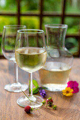 Summer tasting of cold white wine on sunny garden terrace with wooden pergola