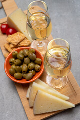 Glasses of dry fino sherry wine served with spanish tapas, manchego cheese, green olives, cheese crackers