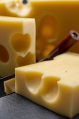 Block of Swiss medium-hard yellow cheese emmental or emmentaler with round holes and cheese knife