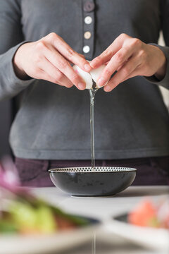 Young female hands cracking egg into a bowl in kitchen.
