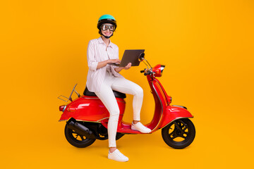 Full body photo of positive biker girl sit motor bike use laptop search browse map online navigation wear helmet goggles striped shirt pants trousers isolated bright shine color background