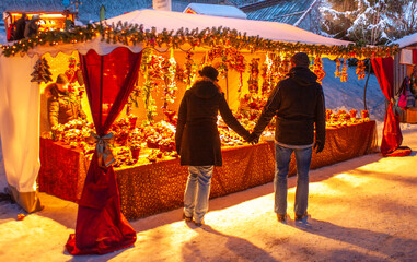 Romantic Christmas market with illuminated shops in wooden huts with gifts and handmade decoration.