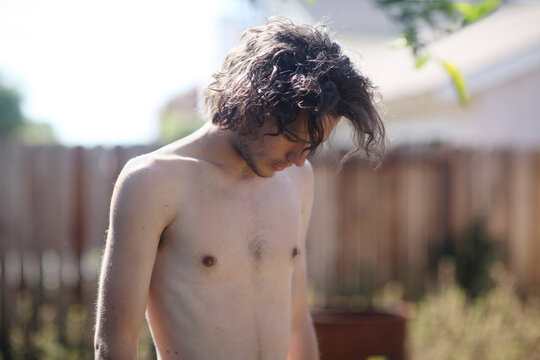 Long haired Young adult Male looking down and shirtless