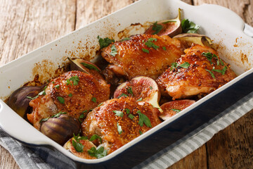 Honey chicken thighs baked with ripe figs, mustard and herbs close-up in a baking dish on the table. horizontal