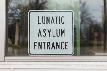 Sign in store window that reads ""Lunatic Asylum Entrance""