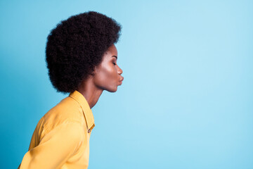 Closeup portrait side profile photo of dark skin big volume hairstyle lady send air kiss blow empty space quarantined boyfriend wear yellow shirt isolated blue color background