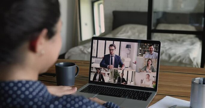 Laptop screen view over businesswoman shoulder distant meeting for negotiations, company remote briefing due covid-19 self-isolation work from home activity. Video call app, easy comfort usage concept