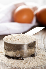 Einkorn siyez whole wheat flour in metal measuring cup on natural background.