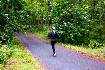 The blonde girl runs along the path in the park. Sports, active, healthy lifestyle.
